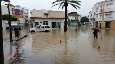 Calle de Barbate inundada de agua, una persona cruz la misma.