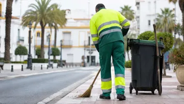 Hombre limpiando una calle con uniforme del servicio de limpieza.