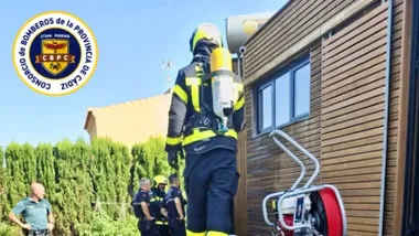 Bombero con equipo de respiración junto a una cabaña de madera.