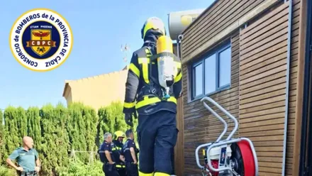 Bombero con equipo de respiración junto a una cabaña de madera.