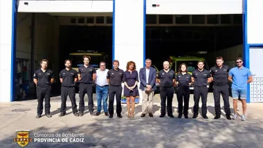 Posado de bomberos y autoridades municipales delante de un hangar.