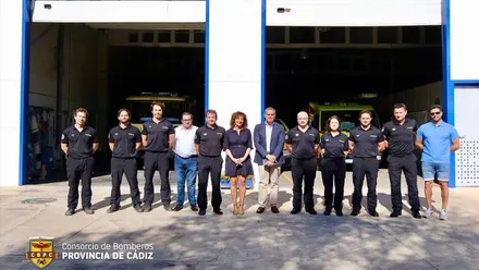 Posado de bomberos y autoridades municipales delante de un hangar.