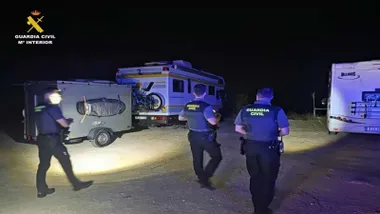 Tres agentes de la Guardia Civil por la noche junto a las autocaravanas.