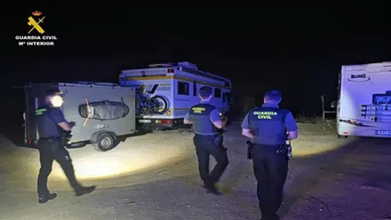 Tres agentes de la Guardia Civil por la noche junto a las autocaravanas.
