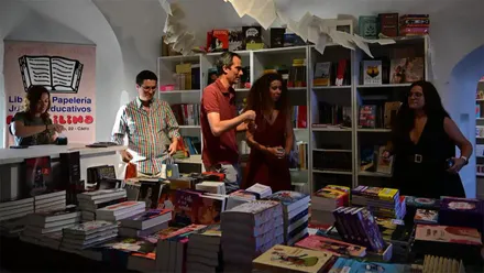 Varias personas observan libros en la Casamata de la Librería Plastilina en la Feria del Libro 2026 de Cádiz