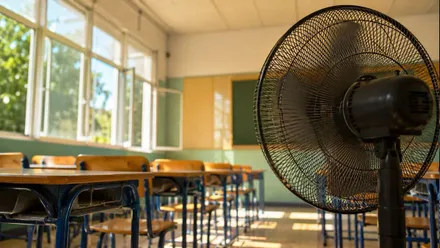 Ventilador y ventanas abiertas para combatir el calor en un colegio.