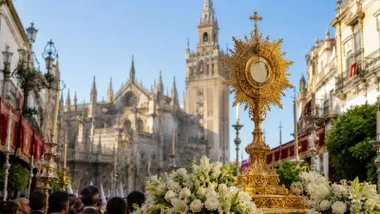 La Sagrada Forma en su relicario y, al fondo, la Giralda de Sevilla.