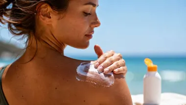 Crema solar blanca siendo extendida por una mujer en su hombro.
