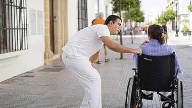 Hombre atiende a una mujer en silla de ruedas.