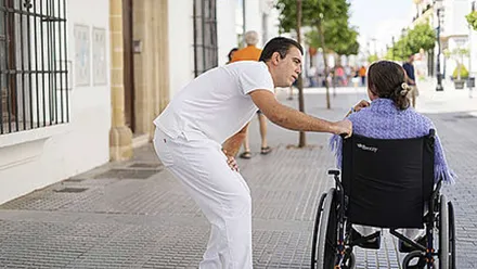 Hombre atiende a una mujer en silla de ruedas.