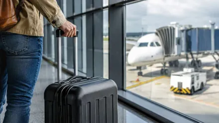Persona con una maleta tipo equipaje de mano dispuesta a embarcar en un avión.