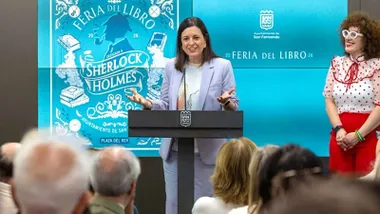 Patricia Cavada, de chaqueta azulona y tras ella el cartel de la Feria del Libro de San Fernando.