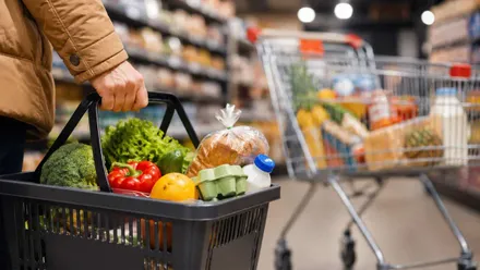 Supermercado con carros y cesta con productos básicos.