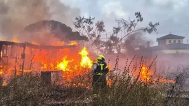 Llamas en la casa abandonada con un bombero tratando de extinguir el incendio.