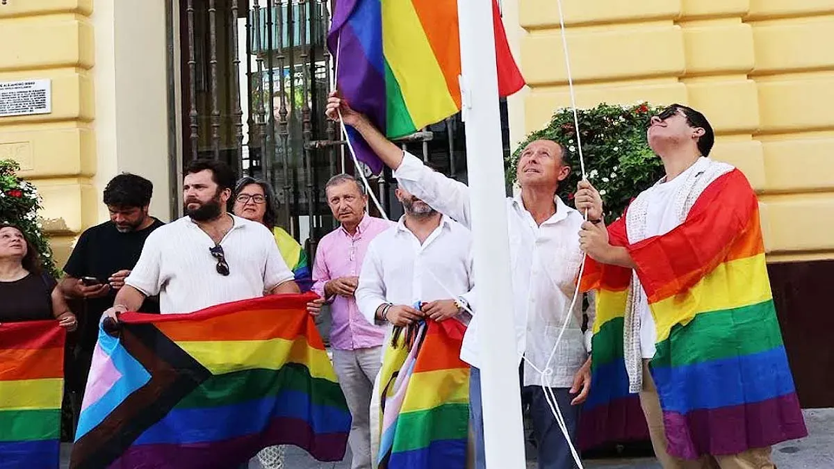 bandera multicolor del Orgullo, con el alcalde y otras personas.