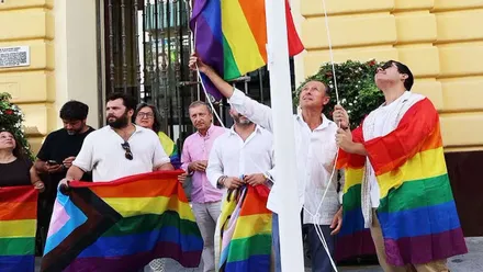 bandera multicolor del Orgullo, con el alcalde y otras personas.