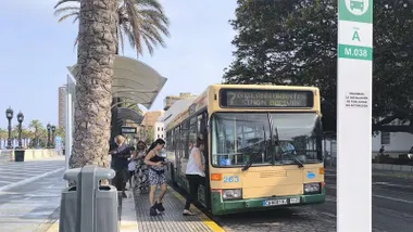 Varias personas suben a un autobús urbano de la línea 7 en una parada situada junto a la playa de La Caleta, en Cádiz.