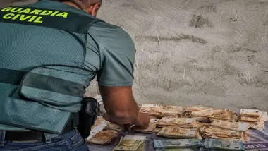 Dinero intervenido por la Guardia Civil y un agente contando dinero.