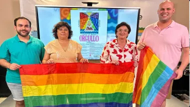 Alcaldesa y delegados sosteniendo la bandera multicolor.