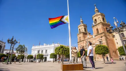 Dos personas izando la bandera del Orgullo en San Fernando.