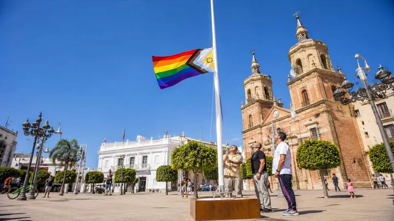 Dos personas izando la bandera del Orgullo en San Fernando.