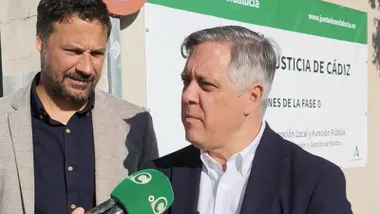 El protavoz del PSOE, Oscar Torres junto al también concejal socialista Jose Macías ante el cartel de la obra de la Ciudad de la Justicia.