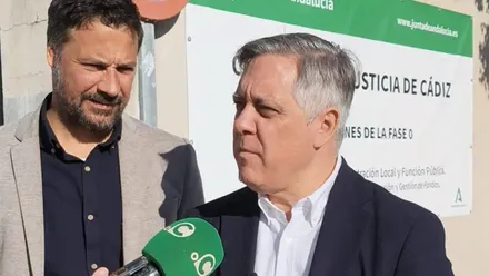 El protavoz del PSOE, Oscar Torres junto al también concejal socialista Jose Macías ante el cartel de la obra de la Ciudad de la Justicia.