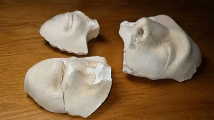 Dos rostros de material pétreo retiradas del cementerio.