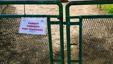 Cancela verde con un cartel en el que se explica que el parque esta cerrado.