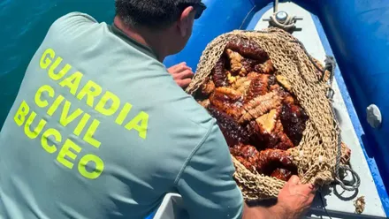 Un agente del GEAS con una bolsa recuperada durante la inmersión, en a una embarcación oficial de la Guardia Civil.
