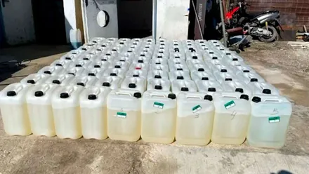 Garrafas de gasolina que muestran el combustible en el patio de una casa cerca de una zona de almacén.