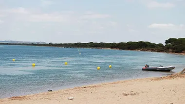 Playa con boyas y una barca, es la playa de Río San Pedro en Puerto Real.