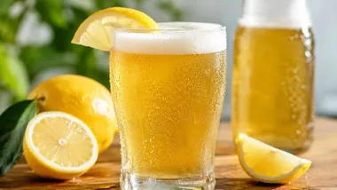 Cerveza en un vaso con limón tras ella.