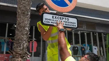 Operarios municipales instalando una nueva señal de aparcamiento reservado para personas con movilidad reducida en una calle de Cádiz, con la nueva nomenclatura visible en primer plano.