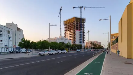 Vista de la Torre Abu en fase de construcción junto a la avenida de la Sanidad Pública de Cádiz, con varias personas caminando bajo un cielo despejado en una jornada estable marcada por el viento de Poniente y temperaturas agradables.