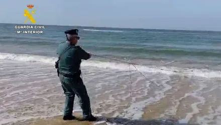 Playa en la que hay un agente de la Guardia Civil tirando de una red.