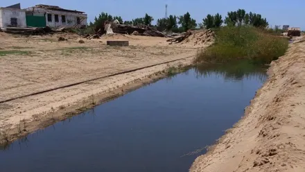 Canal de agua en Bonanza con vegetación y casas.