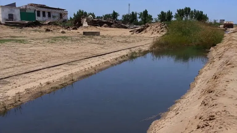 Canal de agua en Bonanza con vegetación y casas.