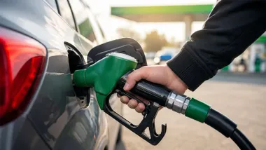 Mano con una manguera de gasolina sin plomo 95 reposando en un coche.