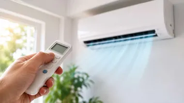 Aire acondicionado y una mano cambiando la temperatura y dirección del mismo.