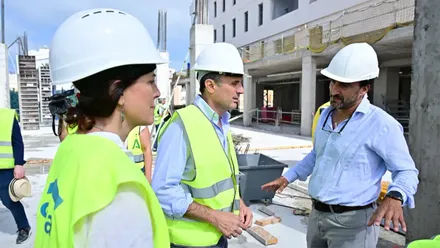 Bruno García y Ana Sanjuán, con casco y chaleco reflectante, conversan con un responsable de la obra durante la visita a la promoción de viviendas protegidas de la avenida de Marconi, con la estructura del edificio en construcción al fondo.