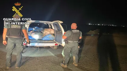 Coche 4x4 cargado con fardos de droga y agentes de la Guardia Civil en el exterior.