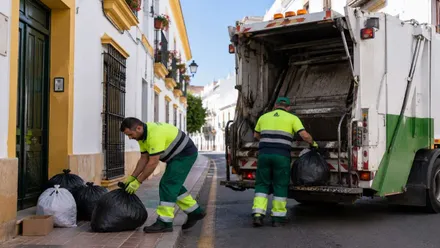 Basura siendo recogida por los operarios junto al camión.