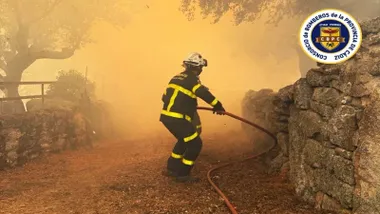 Bombero en una zona de incendios, se ve el resplandor de las llamas.
