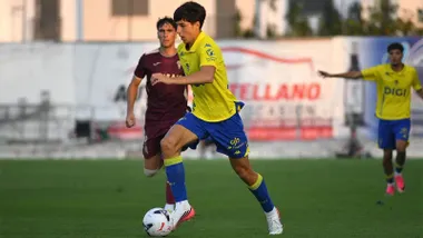 Ibon Sánchez, con la equipación amarilla y azul del Cádiz CF, avanza con el balón mientras un jugador del Córdoba CF le sigue por detrás durante el partido disputado en El Palmar.