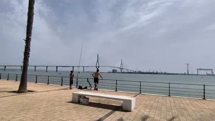 Dos personas pescan en la Bahía en Cádiz, con el Puente Constitución de 1812 al fondo.