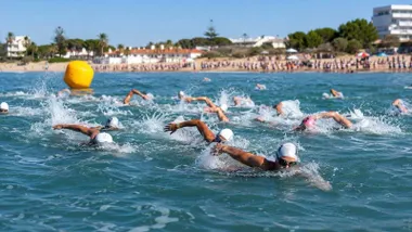 Muchas personas nadando en una playa, dentro de una competición.