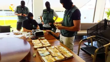 Mesa con dinero y varios agentes de la Guardia Civil contando las cantidades.