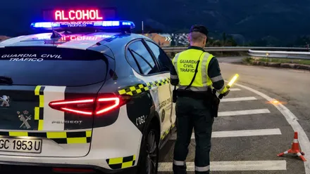 Automóvil y agente de la Guardia Civil haciendo un control de alcoholemia en una carretera.