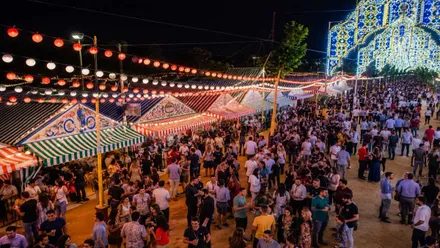 Casetas y personas disfrutando, en la noche, de la Feria de San Fernando.